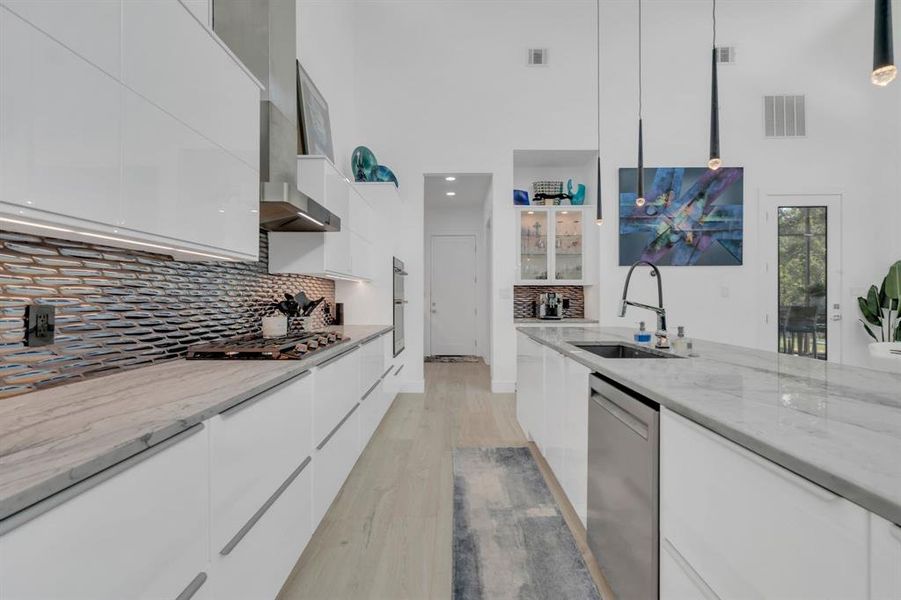 Kitchen featuring white cabinetry, modern cabinets, light stone countertops, and a towering ceiling