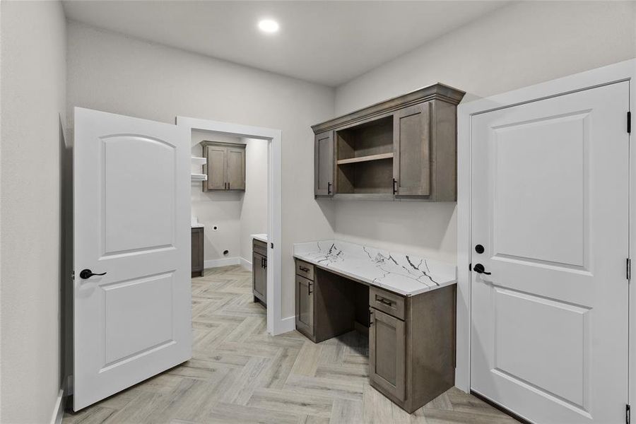 Kitchen featuring dark brown cabinetry, light stone countertops, and light parquet floors