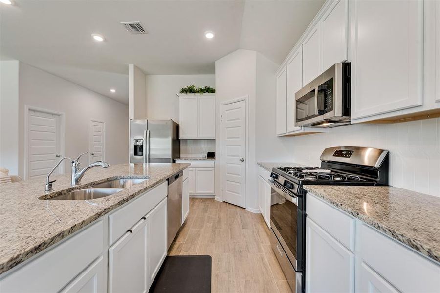 Kitchen with appliances with stainless steel finishes, recessed lighting, white cabinetry, light wood-style flooring, and decorative backsplash Kitchen with appliances with stainless steel finishes, recessed lighting, white cabinetry, light wood-style flooring, and decorative backsplash