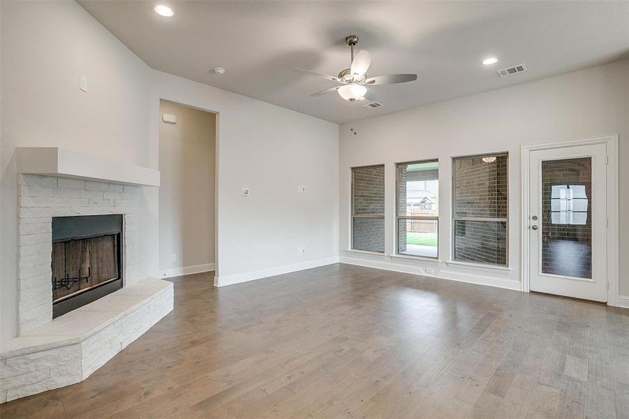 Unfurnished living room featuring light hardwood / wood-style flooring, ceiling fan, and a fireplace