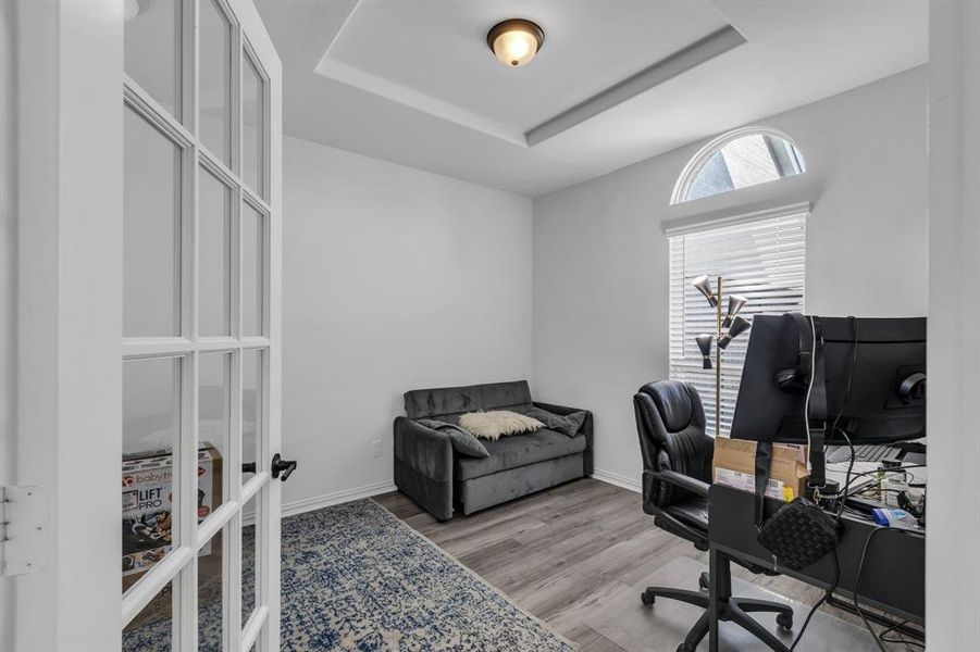 Home office featuring light hardwood / wood-style floors and a tray ceiling