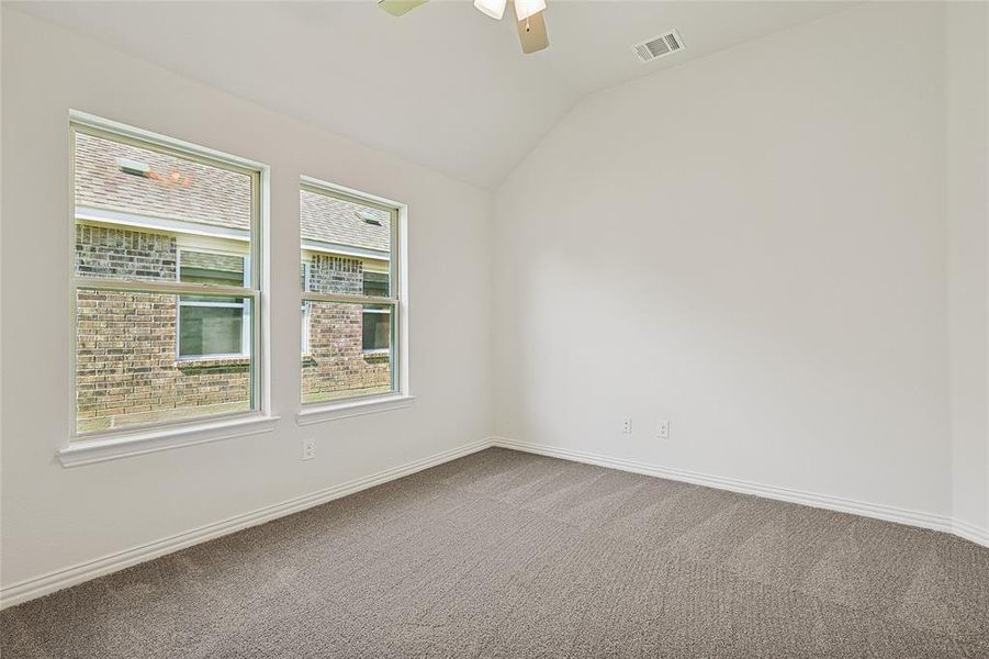 Spare room with a healthy amount of sunlight, carpet, and vaulted ceiling