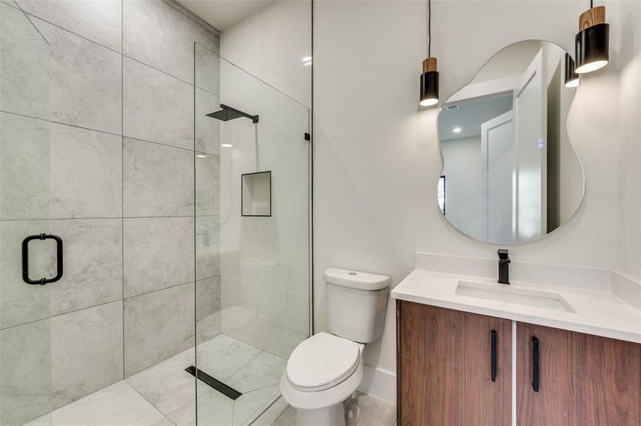 Contemporary bathroom featuring a glass-enclosed shower with large format tile, a built-in shower niche, and a matte black rain shower head