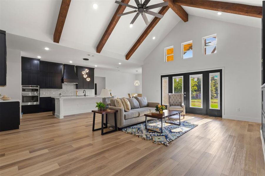 Living area with high vaulted ceiling, beam ceiling, light wood-style flooring, ceiling fan, and recessed lighting