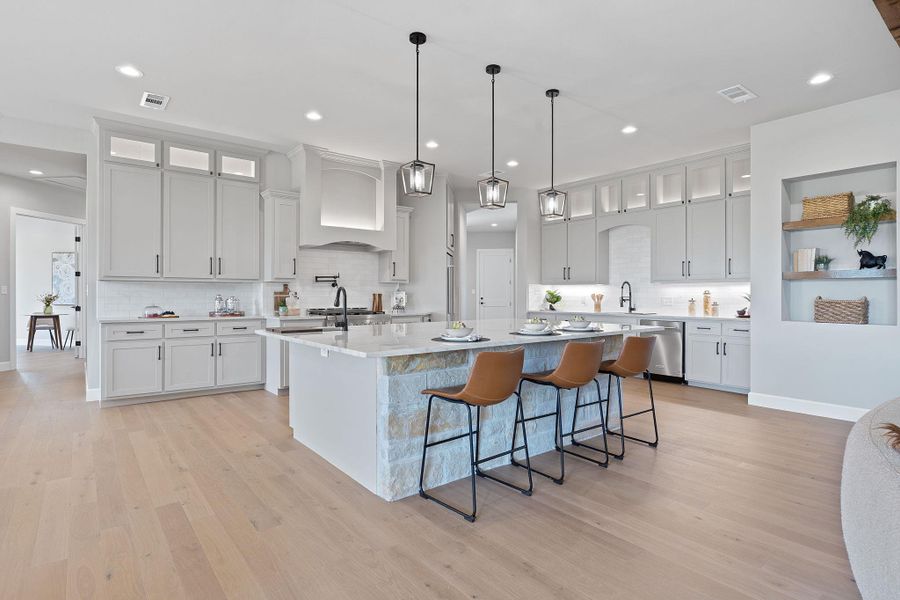 Kitchen with custom exhaust hood, stainless steel dishwasher, a spacious island, light wood-style floors, and recessed lighting