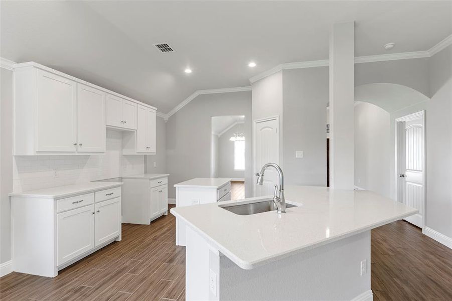 Kitchen with ornamental molding, sink, a center island with sink, white cabinets, and hardwood / wood-style floors