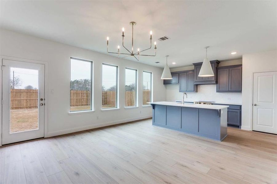 Kitchen featuring a chandelier, a sink, light countertops, backsplash, and custom range hood
