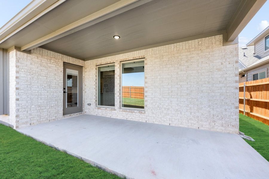 Covered back patio with concrete slab, light brick exterior, and fenced backyard