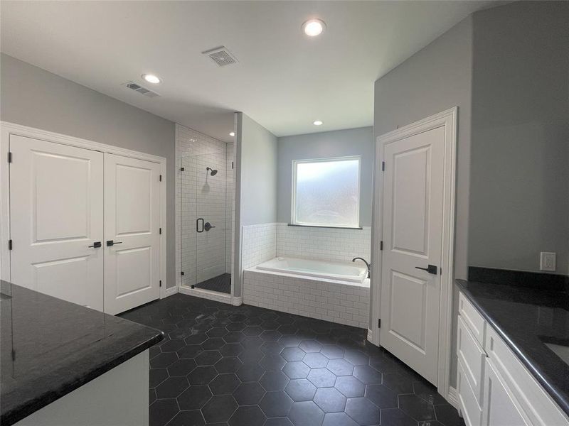 Full bath with vanity, a shower stall, a bath, and dark tile patterned flooring