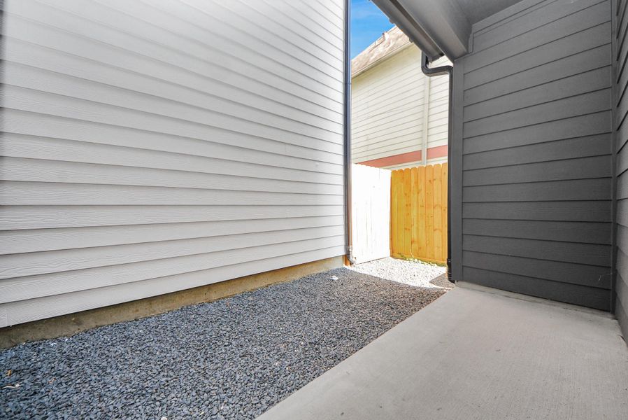 Step into this narrow outdoor side area between homes, with gravel ground and siding walls. A wooden fence at the end provides privacy while maintaining a clean and orderly appearance.