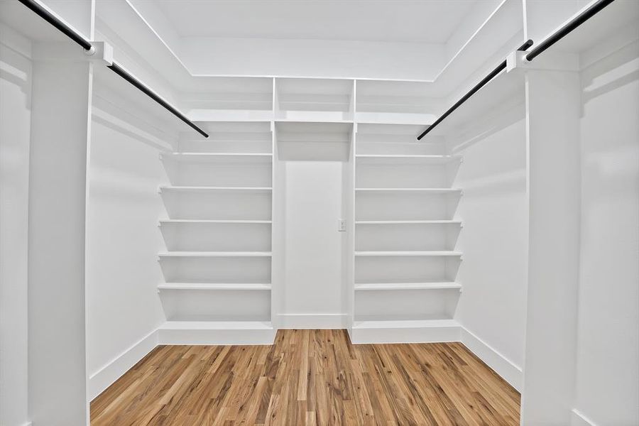 This custom closet features extensive shelving, hanging rods, and hardwood floors