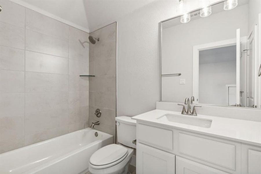 Full bathroom with vanity, tiled shower / bath, and toilet