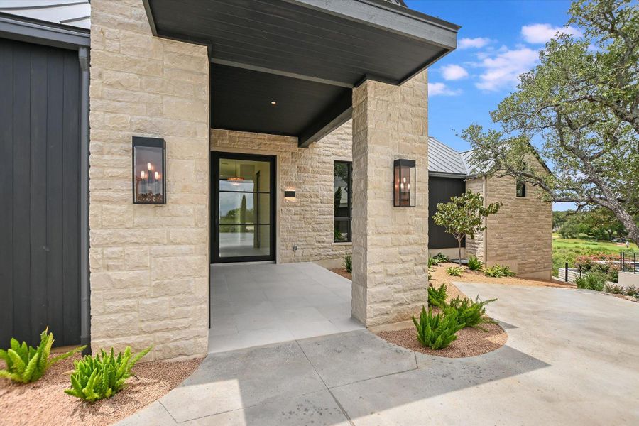 A striking stone facade with a modern black door and inviting outdoor lighting creates a welcoming entry.