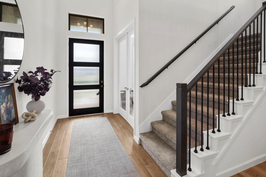 Elegant foyer highlighting the modern staircase with wrought iron spindles and the French doors leading into the private home office. Elegant foyer highlighting the modern staircase with wrought iron spindles and the French doors leading into the private home office.