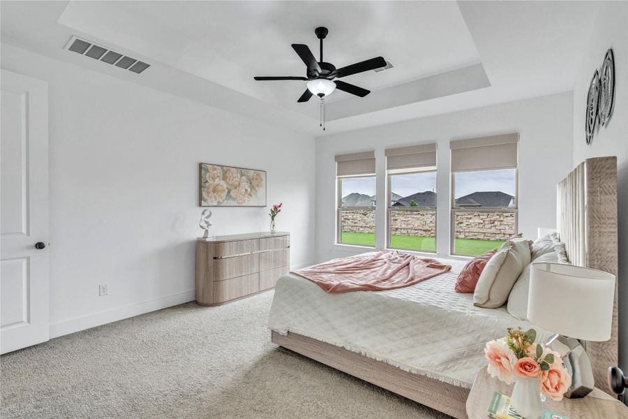 Well-lit sleeping quarters with a ceiling fan, plush carpeting, and generous windows overlooking a verdant lawn.