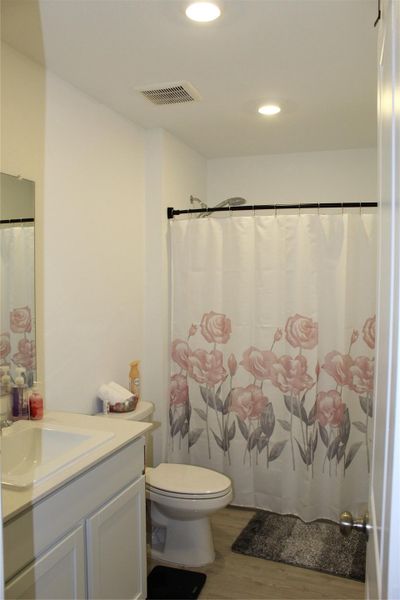Full bath with light wood-style flooring, vanity, a shower with shower curtain, and recessed lighting
