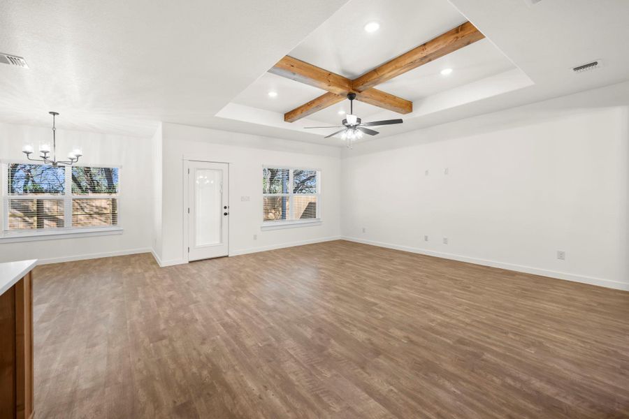 Exposed wood beams adorn the ceiling, complementing the rich flooring in this luminous living area.
