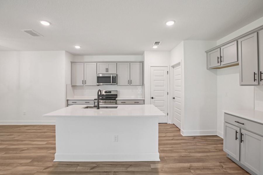 Elegant gray cabinetry, quartz island, and hardwood floors define this Spring Hill luxury kitchen.