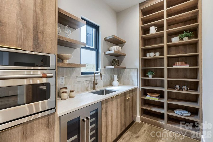 Dedicated scullery with additional sink, wine fridge, cabinetry, and storage