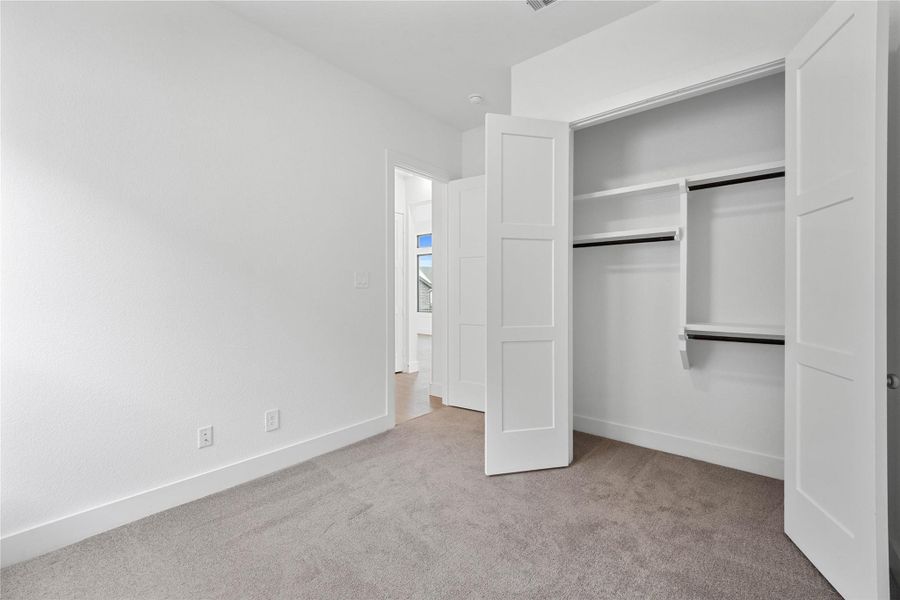 The secondary closet with built in shelving and multiple rows to hang clothing.