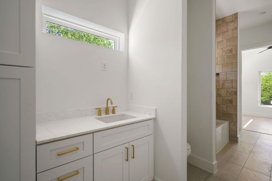 Bathroom featuring vanity, tile patterned flooring, toilet, baseboards, and a bathtub