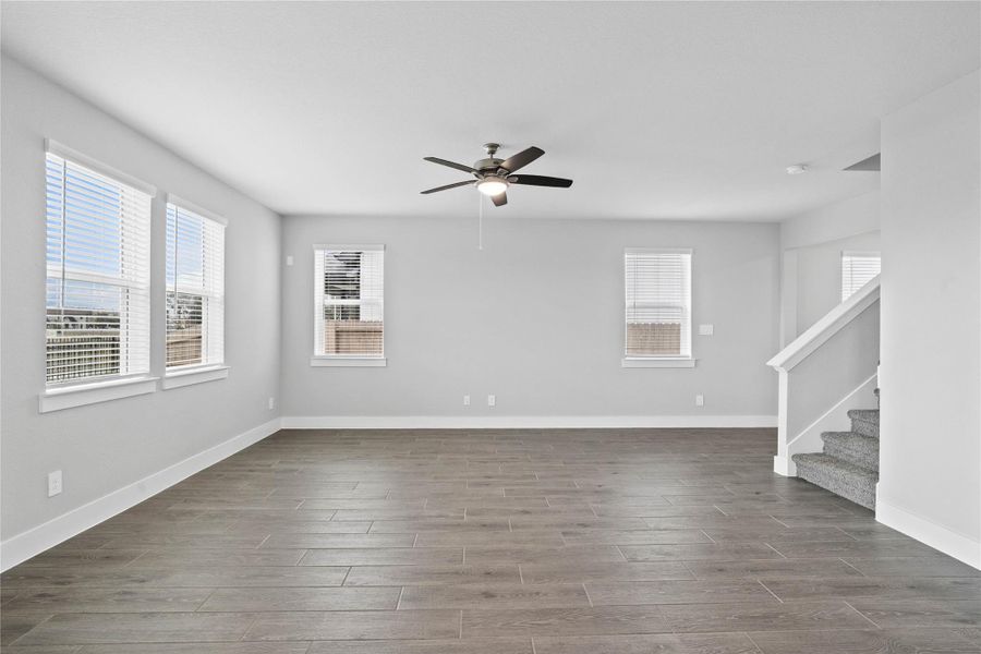 A bright and airy open-concept space featuring modern wood-look tile flooring, abundant natural light, and a stylish ceiling fan, creating an inviting atmosphere for relaxation or entertaining. A bright and airy open-concept space featuring modern wood-look tile flooring, abundant natural light, and a stylish ceiling fan, creating an inviting atmosphere for relaxation or entertaining.