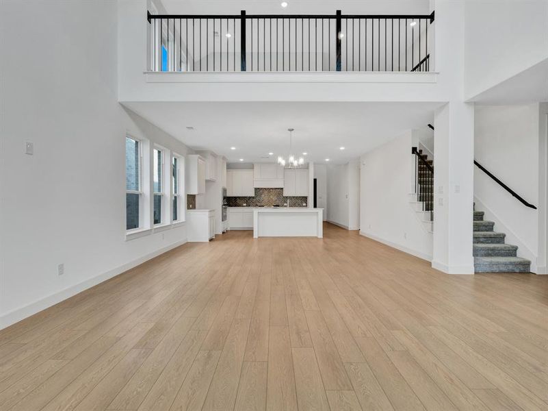 Unfurnished living room with a high ceiling, a chandelier, and light hardwood / wood-style flooring