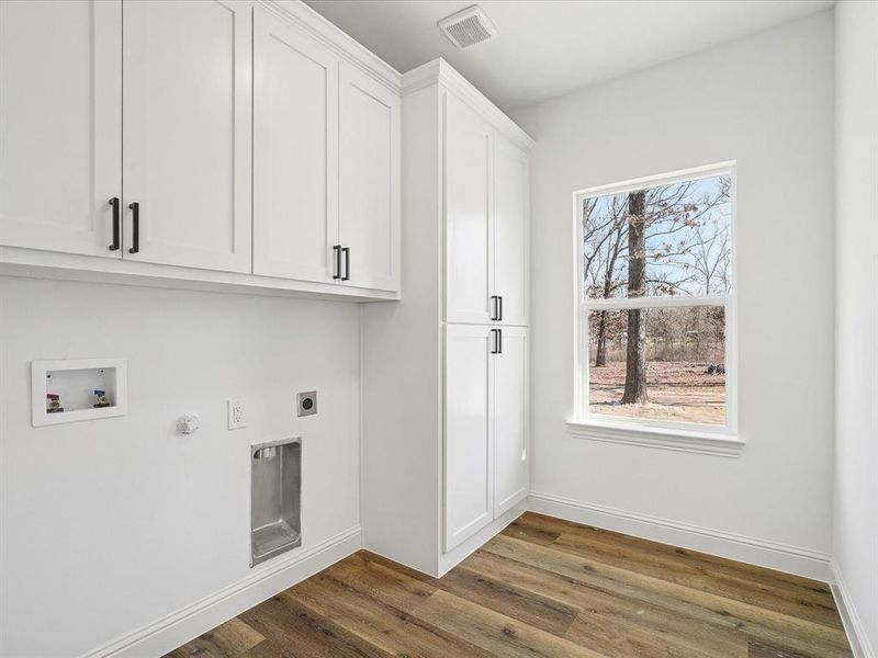Laundry room featuring cabinet space, dark wood finished floors, hookup for an electric dryer, gas dryer hookup, and hookup for a washing machine