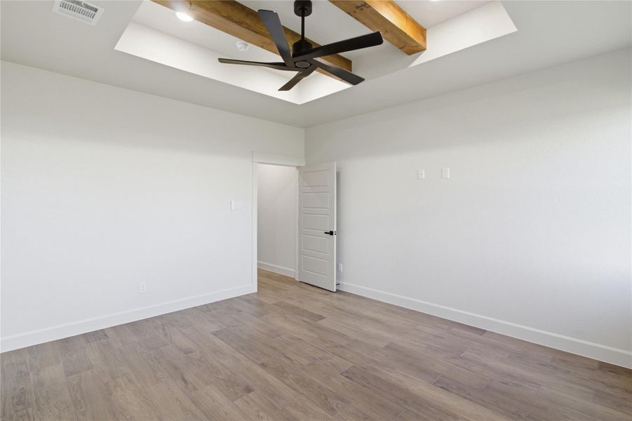 A well-lit bedroom features a vaulted ceiling with exposed wooden beams and a contemporary ceiling fan. A well-lit bedroom features a vaulted ceiling with exposed wooden beams and a contemporary ceiling fan.