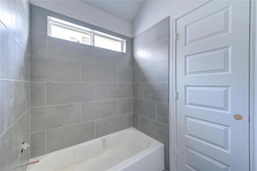 This bathroom features a tub with contemporary tile work, offering a blend of style and functionality. The sleek design and neutral tones provide a modern canvas. **This image is from another Saratoga Home - Artemis floorplan.**