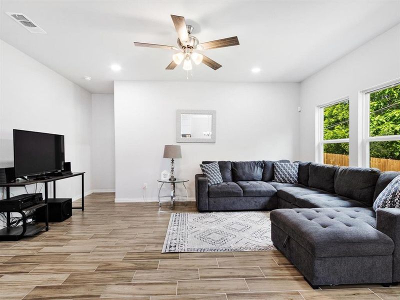 Spacious living area featuring wood-finish flooring and a contemporary ceiling fan with lighting