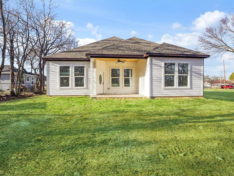 Rear view of house featuring ceiling fan, roof with shingles, a patio, and a yard Rear view of house featuring ceiling fan, roof with shingles, a patio, and a yard