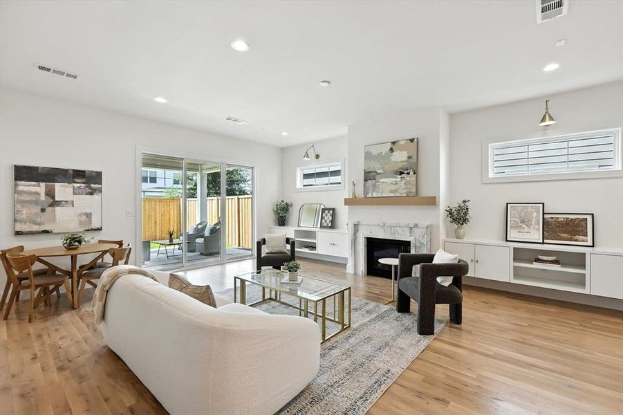Living area featuring recessed lighting, light wood-type flooring, and a premium fireplace Living area featuring recessed lighting, light wood-type flooring, and a premium fireplace