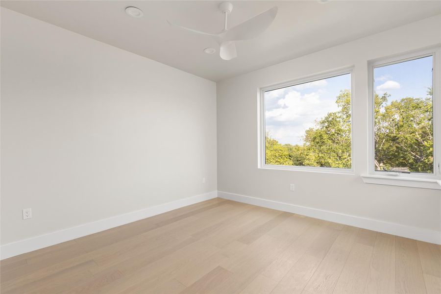 Generous windows frame peaceful treetop views from this light-filled room with wood flooring.