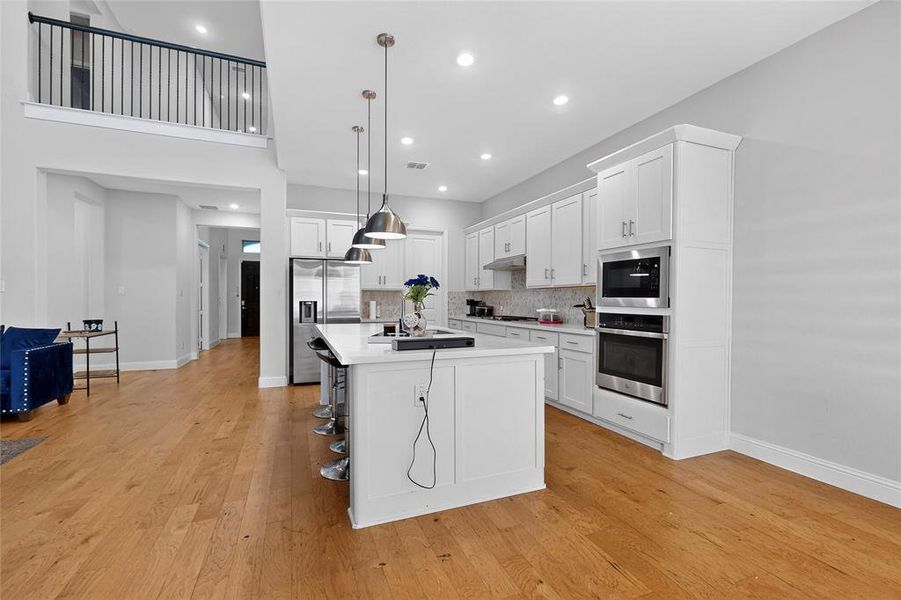 Kitchen with hanging light fixtures, white cabinetry, backsplash, and recessed lighting