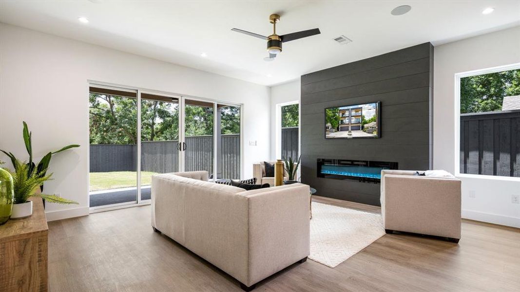 Living room featuring a healthy amount of sunlight, wood-type flooring, a large fireplace, and ceiling fan