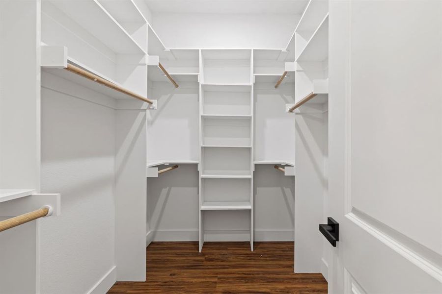 Walk in closet with dark wood-style floors