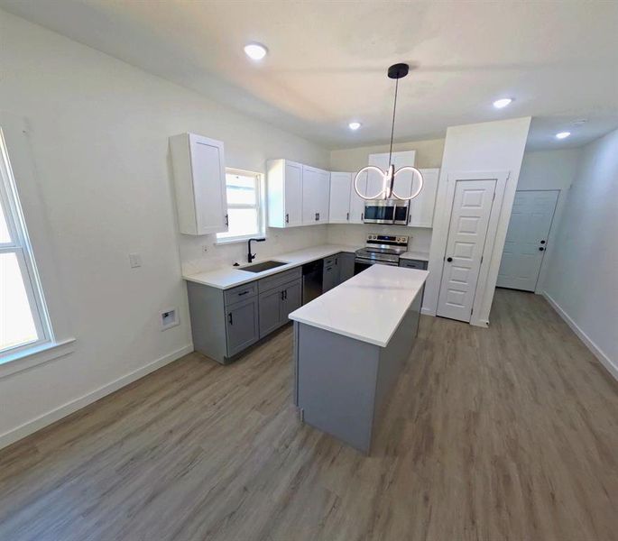 Kitchen with gray cabinets, white cabinetry, stainless steel appliances, a kitchen island, and hanging light fixtures Kitchen with gray cabinets, white cabinetry, stainless steel appliances, a kitchen island, and hanging light fixtures