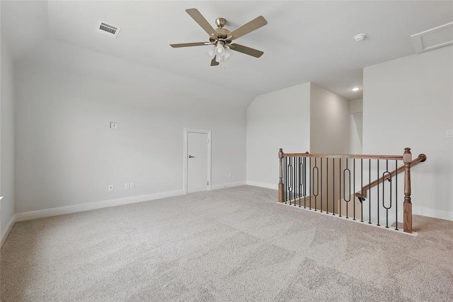 Carpeted spare room featuring visible vents, baseboards, recessed lighting, a ceiling fan, and lofted ceiling