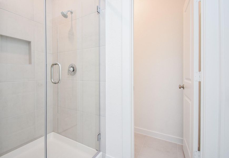 The roomy walk-in, glass enclosed shower sits right across the door to your primary walk-in closet.