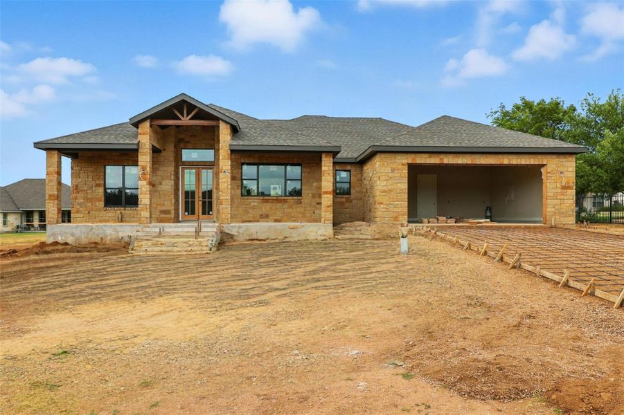 View of front of property with roof with shingles, stone siding, a garage, and covered porch View of front of property with roof with shingles, stone siding, a garage, and covered porch