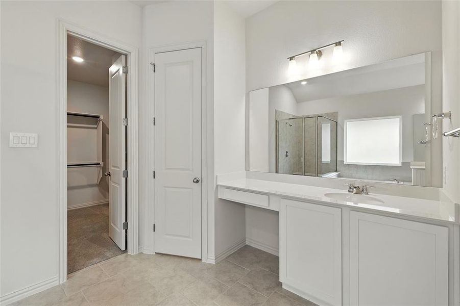 Bathroom with a shower stall, vanity, a spacious closet, and light tile patterned floors Bathroom with a shower stall, vanity, a spacious closet, and light tile patterned floors