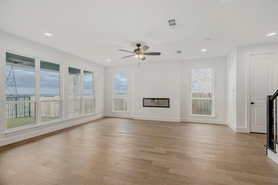 Spacious room featuring wood-finish flooring, recessed lighting, and a contemporary linear fireplace