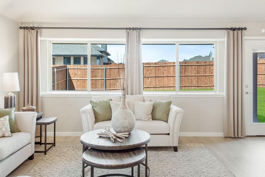 Living room with white sofas, round wood coffee table, and large windows overlooking a fenced backyard Living room with white sofas, round wood coffee table, and large windows overlooking a fenced backyard