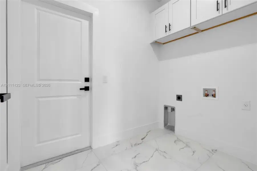 Laundry room with washer/dryer hookups and overhead cabinet storage.