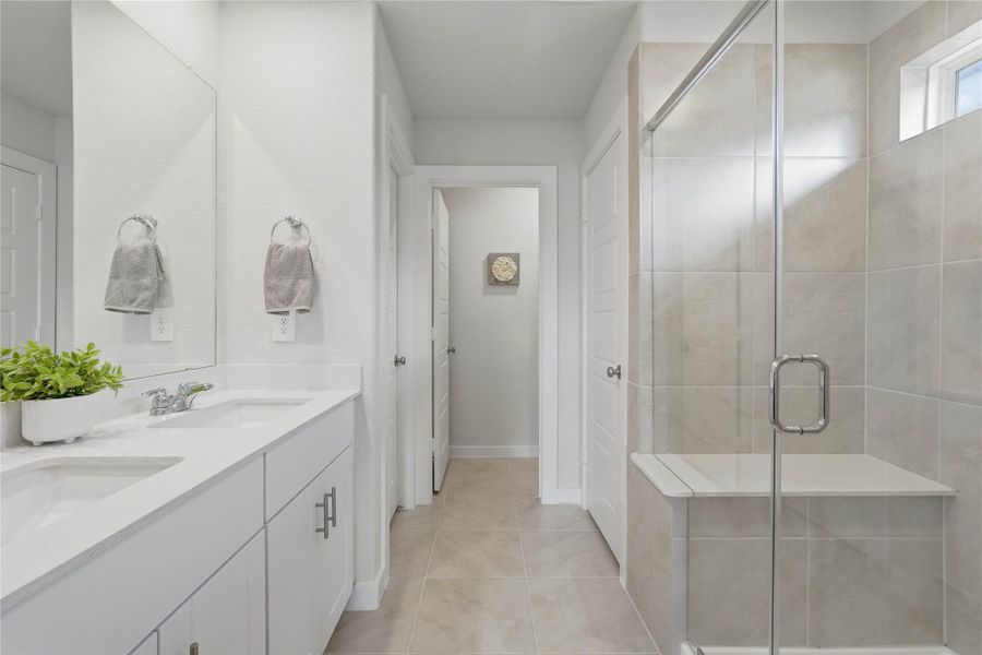 The primary bath features double sinks, a large walk-in shower, and a the convenience of a linen closet.