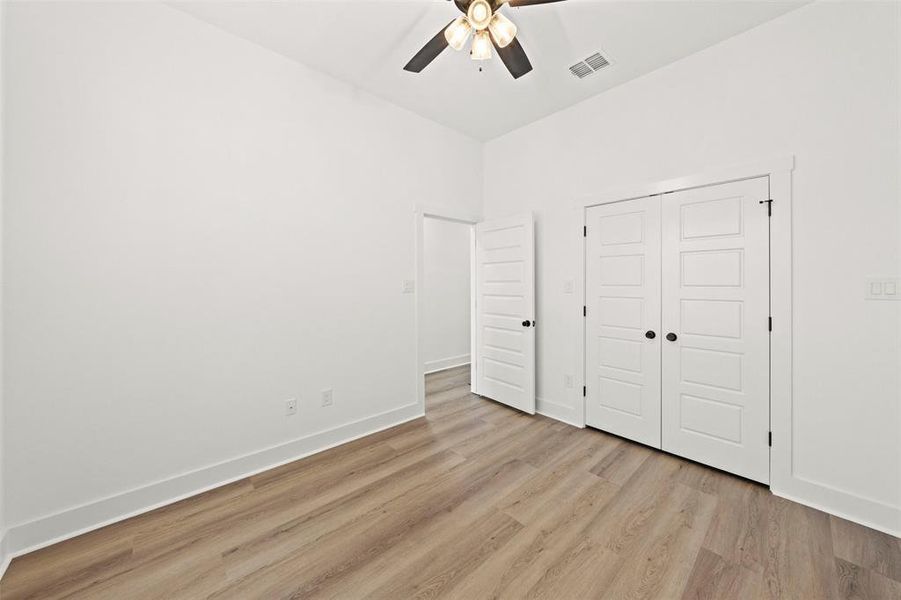 Unfurnished bedroom featuring light wood-type flooring, a closet, and ceiling fan