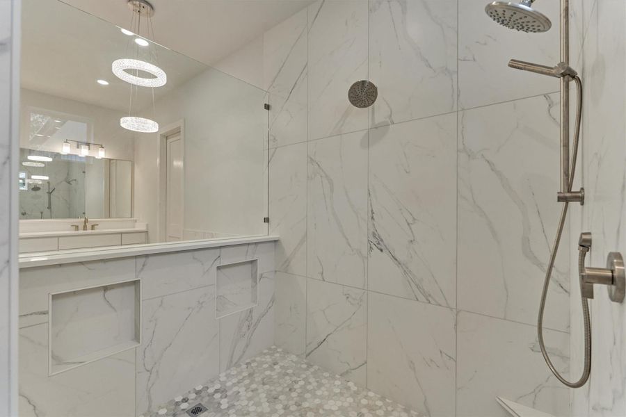 Elegant walk-in shower with floor-to-ceiling marble-look tile, dual built-in niches, and a spa-grade shower system—perfectly framed by designer lighting for a serene retreat.