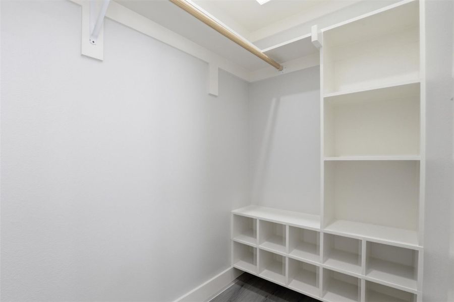 Built-in white storage system featuring open shelving, multiple cubbies, and a hanging rod