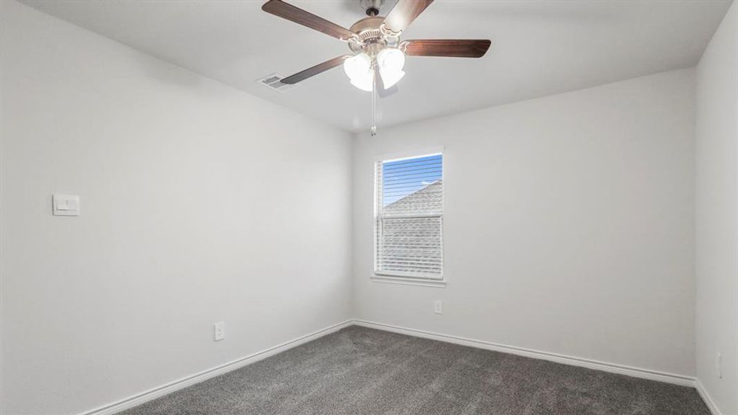 Empty room with dark carpet and a ceiling fan Empty room with dark carpet and a ceiling fan
